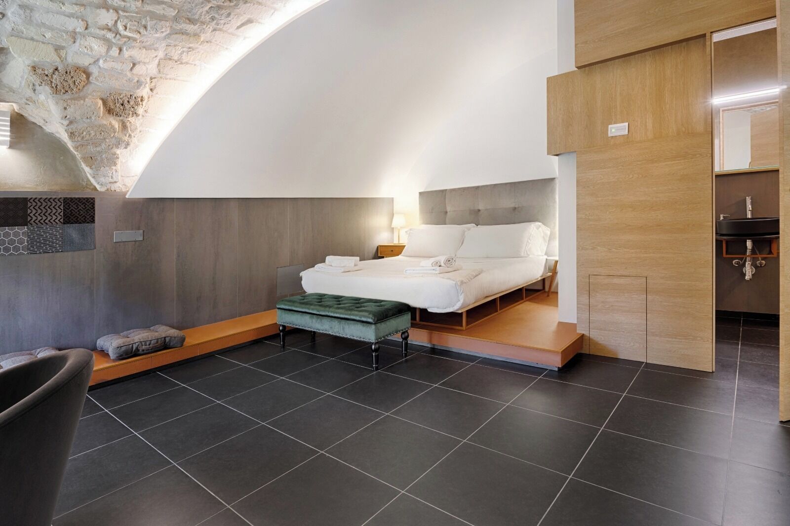 Un dormitorio moderno con cama, banca y mesita de noche.