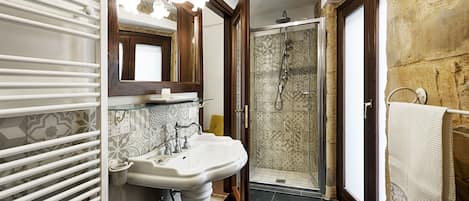 A bathroom with a white pedestal sink, a glass shower enclosure, and a towel rack.