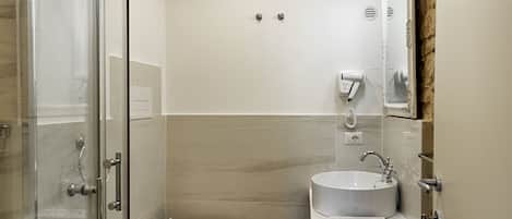 Un baño moderno con cabina de ducha de vidrio, inodoro y lavabo con espejo.