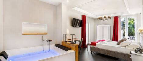 A modern hotel room with a bathtub, a bed, a desk, and a TV.