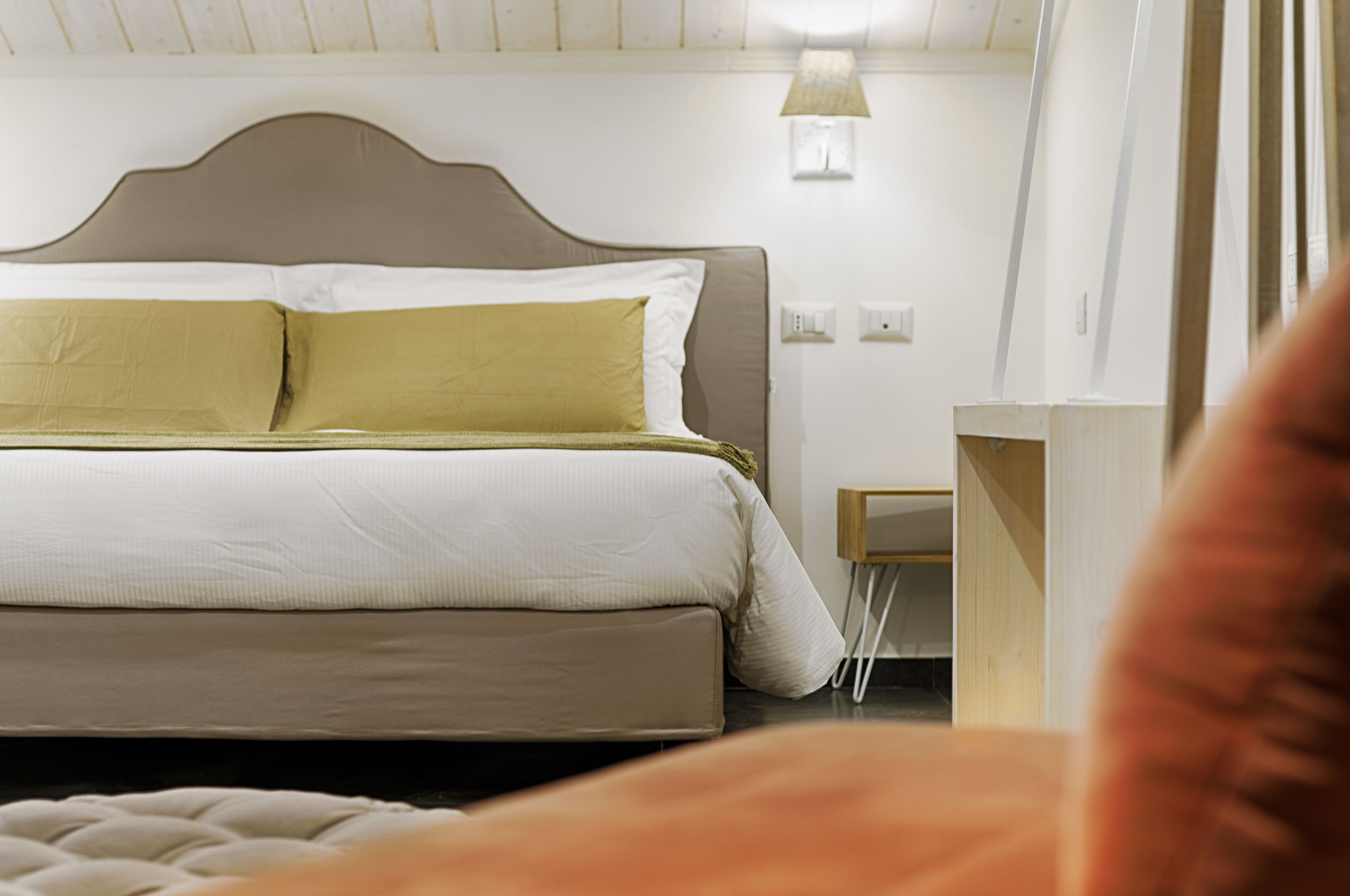 Un dormitorio con cama, mesita de noche, lámpara y otro mueble auxiliar.