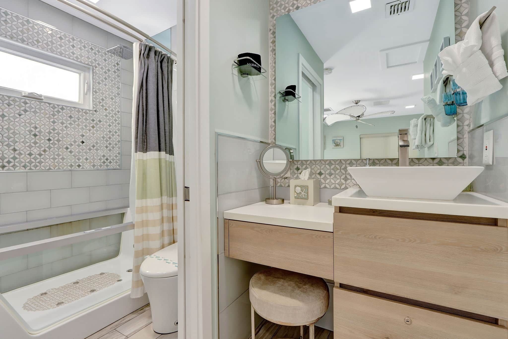 Ein Badezimmer mit Badewanne, Toilette, Waschtisch mit Spiegel und Duschvorhang.