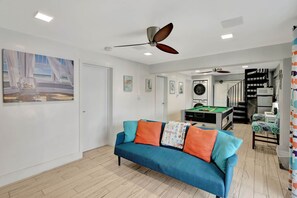 A living room with a blue sofa, ceiling fans, a pool table, and a staircase leading to another level. - Waterfront Home 3/2.5,HotTub,2Sup,4Kayaks,Golf Car (Key Largo)