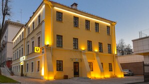 Un edificio amarillo de varios pisos con una entrada en forma de U y una señal con la letra 'U' visible.