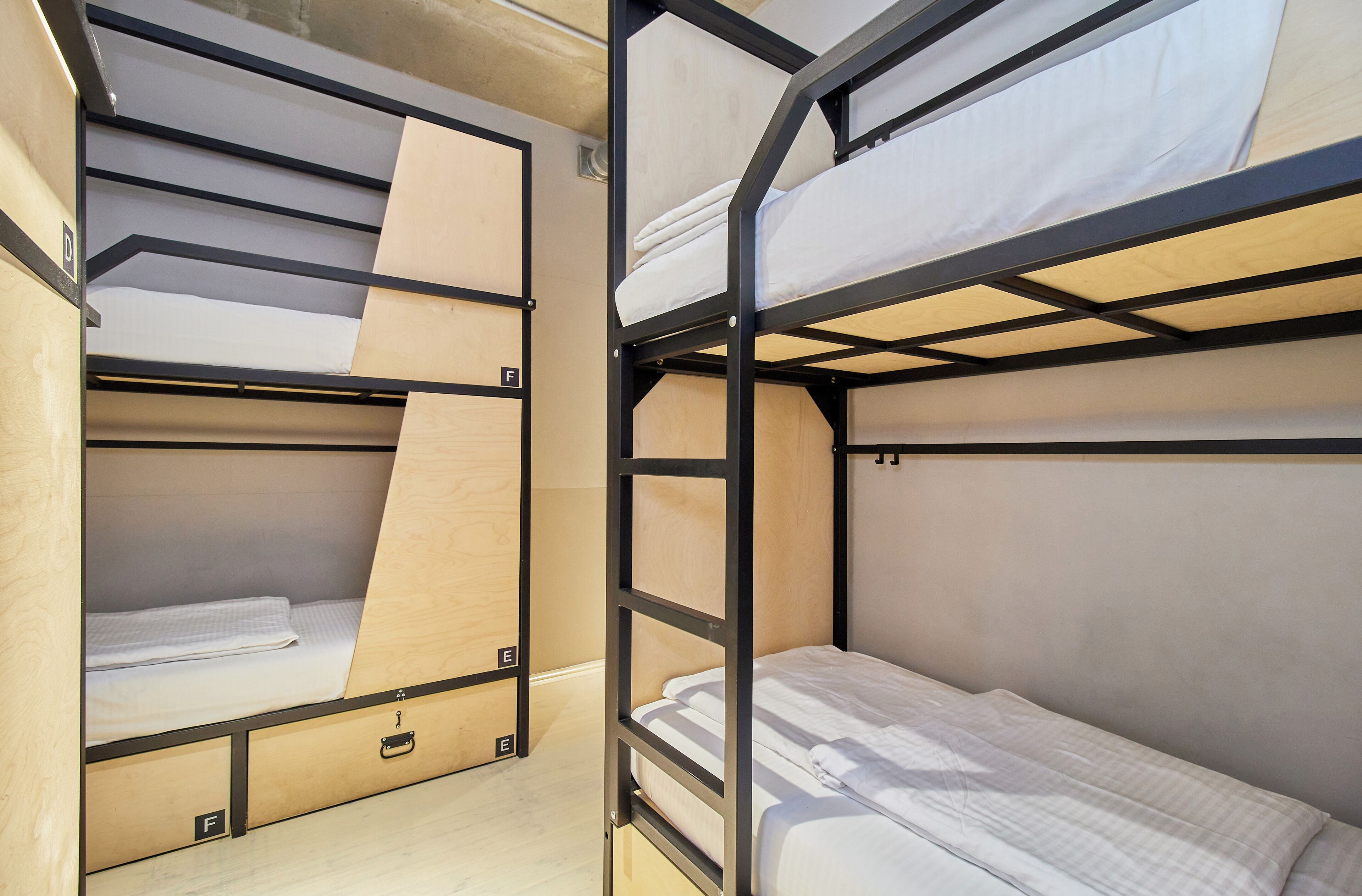 Camas literas con estructura de madera y ropa de cama blanca.