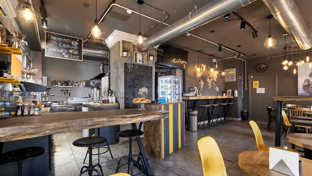 Un café moderno con barra, taburetes y cartel de menú.