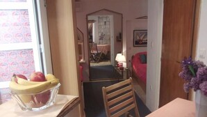 A dining area with a table, chairs, a fruit bowl, a lamp, and a vase with flowers. - Apartments Abjanic - Studio with Terrace - Ilije Sarake 8 (Dubrovnik)