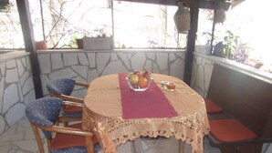 A stone-walled patio with a round table, four chairs, and a bench. - Apartments Abjanic - Studio with Terrace - Ilije Sarake 8 (Dubrovnik)