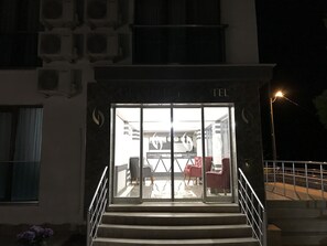 Entrada de hotel con puerta de vidrio, escalones que la conducen y un cartel sobre la puerta.