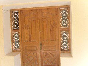 A wooden double door with intricate geometric patterns and decorative metalwork on the sides.