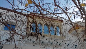 Un bâtiment à la façade blanche, doté de nombreuses fenêtres et d’un balcon orné de balustrades décoratives.
