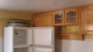 Une cuisine avec un réfrigérateur blanc, des armoires en bois et un dosseret de carrelage jaune.