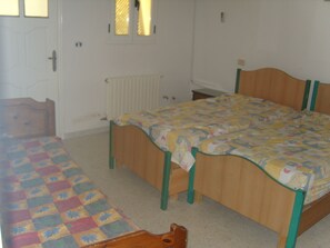 A bedroom with a wooden bed, a wooden chair, and a small table.