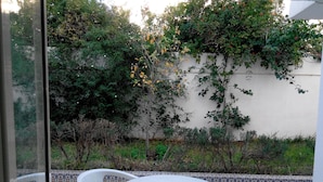Une terrasse avec une table ronde et deux chaises, entourée d’un mur recouvert de carreaux formant un motif décoratif.