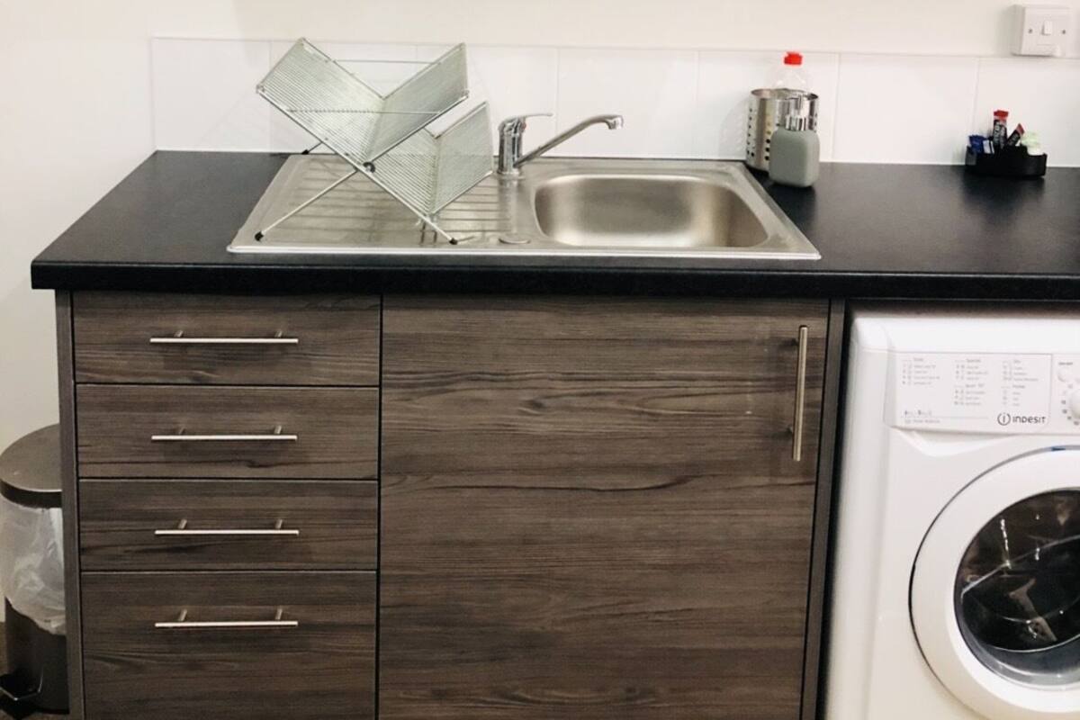 Una cocina con lavavajillas integrado, un fregadero y un armario con espacio de almacenamiento.
