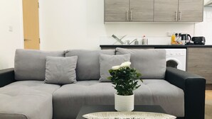 Ein modernes Wohnzimmer mit einem grauen Sofa, einem schwarzen Couchtisch und einer weißen Vase mit Blumen.