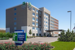 Welcome to Holiday Inn Express & Suites, featuring a modern design with a flat roof and a mix of brick and stone facade.
