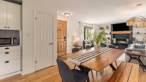 Une cuisine moderne avec des meubles blancs, un four à micro-ondes et un coin repas comprenant une table et des chaises en bois.