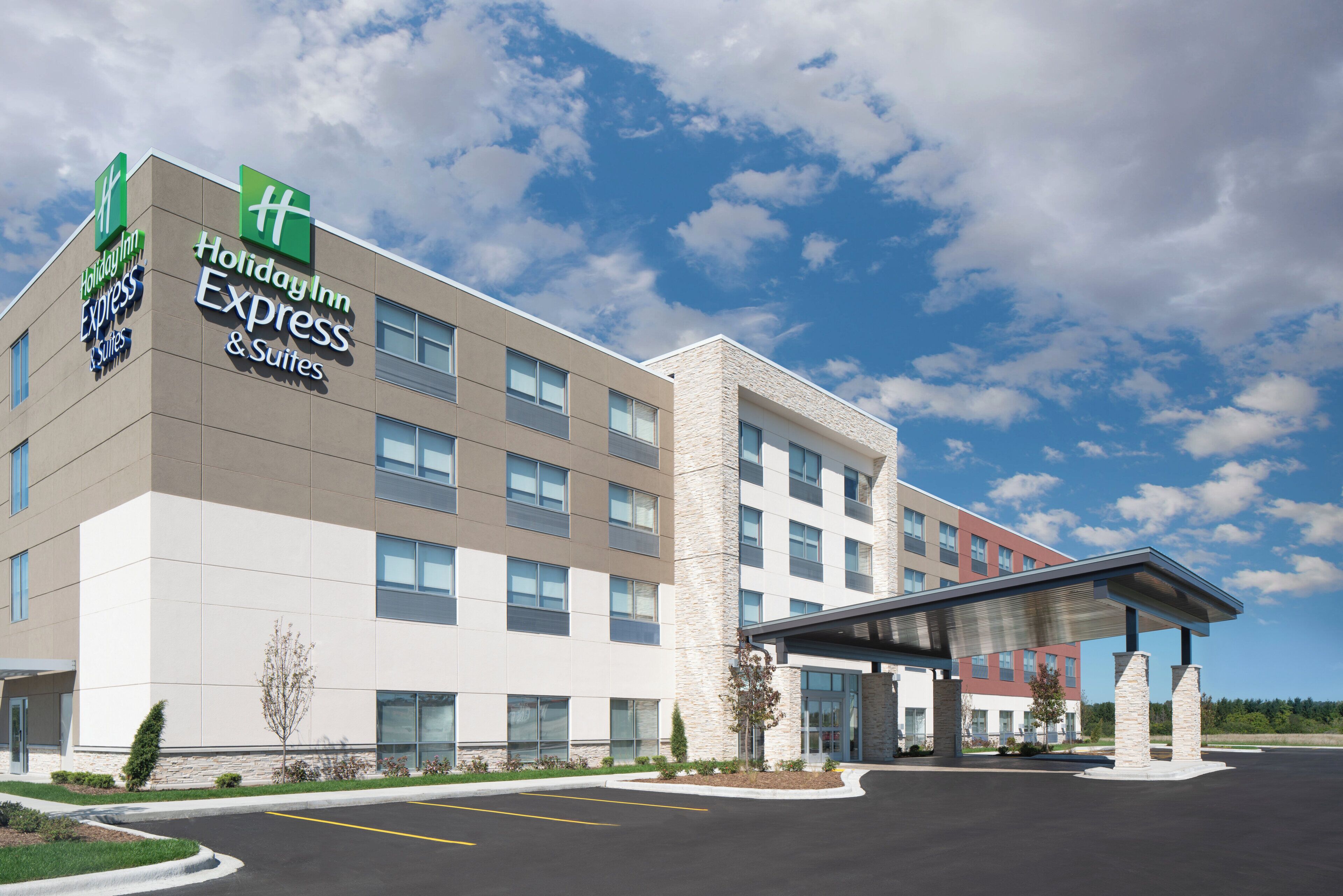 A Holiday Inn Express & Suites hotel with a modern architectural design, featuring a flat facade, large windows, and a covered entrance.
