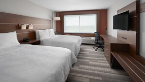 Ein Hotelzimmer mit zwei Betten, einem Fernseher, einem Schreibtisch und einem großen Fenster.