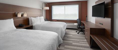 A hotel room with two beds, a TV, a desk, and a large window.