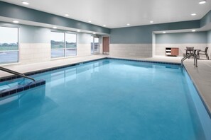 A swimming pool with clear blue water, surrounded by a tiled deck and a seating area with chairs. - Holiday Inn Express & Suites Elkhorn - Lake Geneva Area by IHG (Elkhorn)