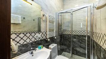 Een moderne badkamer met een marmeren wastafel, toilet, douche met glazen wanden en een handdoekrek.