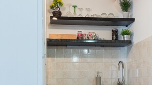 Uma cozinha compacta com armários brancos, forno embutido e bancada com pia.