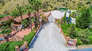 An aerial view of a resort with a paved entrance, palm trees, and a parking area. - Cubo's Mijas Finca Huerta Rica Bambu / shared pool / views (Mijas Pueblo)