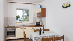 A compact kitchen with a stove, oven, microwave, and a small dining table with chairs.