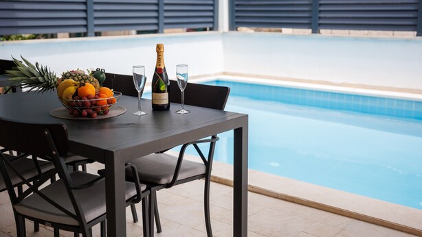 Ein Tisch am Pool mit Früchten, einer Champagnerflasche und Gläsern.