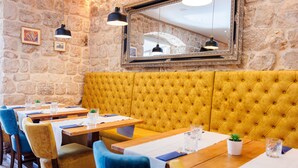 Ein Restaurant mit Steinwänden, gelb gepolsterten Sitzbänken und Holztischen.
