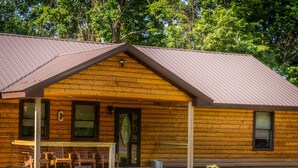 Une cabane en rondins avec une véranda, une table et des chaises à l’extérieur.