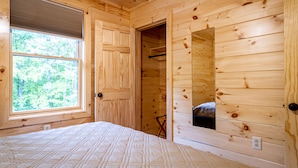 Une pièce dans un chalet en bois, comprenant un lit, une fenêtre et un miroir.