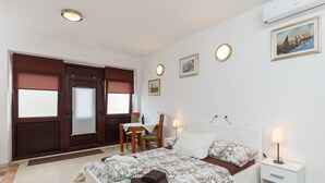 A bedroom with a bed, bedside table, lamp, and a desk with a chair. - Apartments Dia - Studio Apartment with Terrace (Dubrovnik)