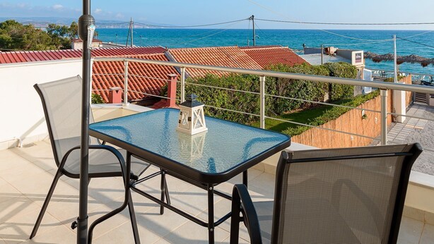 A balcony with a table and chairs, a large umbrella, and a view of the sea. - Studio with sea view (Kokkinos Pirgos)