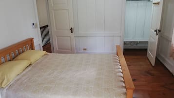 Un dormitorio con una cama de madera, una puerta blanca y un armario.