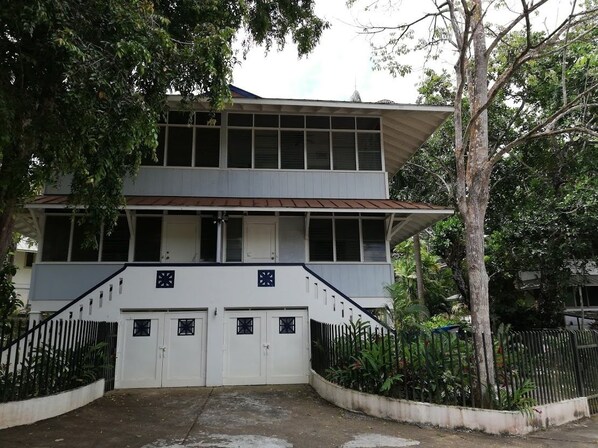 A two-story building with a white facade, a red roof, and a staircase leading to the entrance.