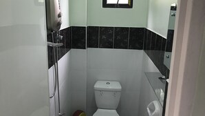 Ein kleines Badezimmer mit Toilette, Dusche und einem Spiegel an der Wand.