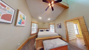 A bedroom with a bed, a ceiling fan, a deer skull wall decoration, and framed artwork.