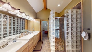 A bathroom with a large mirror, two sinks, and a shower with a glass enclosure.