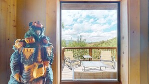 A wooden cabin with a balcony featuring outdoor furniture and a scenic view.