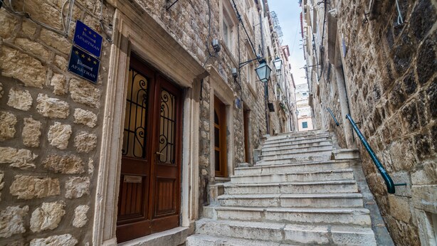 A narrow stone staircase leading to a building with a wooden door and a sign indicating it is an apartment. - Apartment Maru - Two Bedroom Apartment with City View (Dubrovnik)