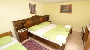 A single-bed room with a wooden headboard, green bedding, a nightstand with a lamp, and two paintings on the walls. - Apartment in Premantura with Garage near Kamenjak (Medulin)