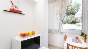 Een keuken met een magnetron, een schaal fruit en een rode en witte schelpdierdecoratie op een plank.