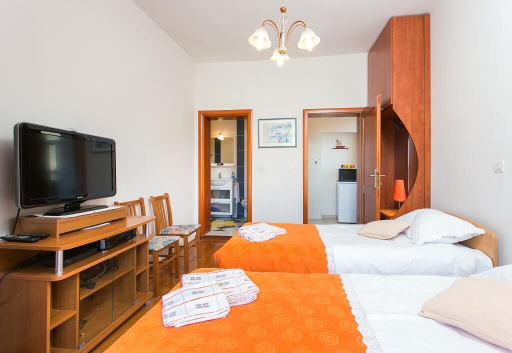 Una camera d'albergo con due letti, una televisione, una scrivania in legno e un armadio.