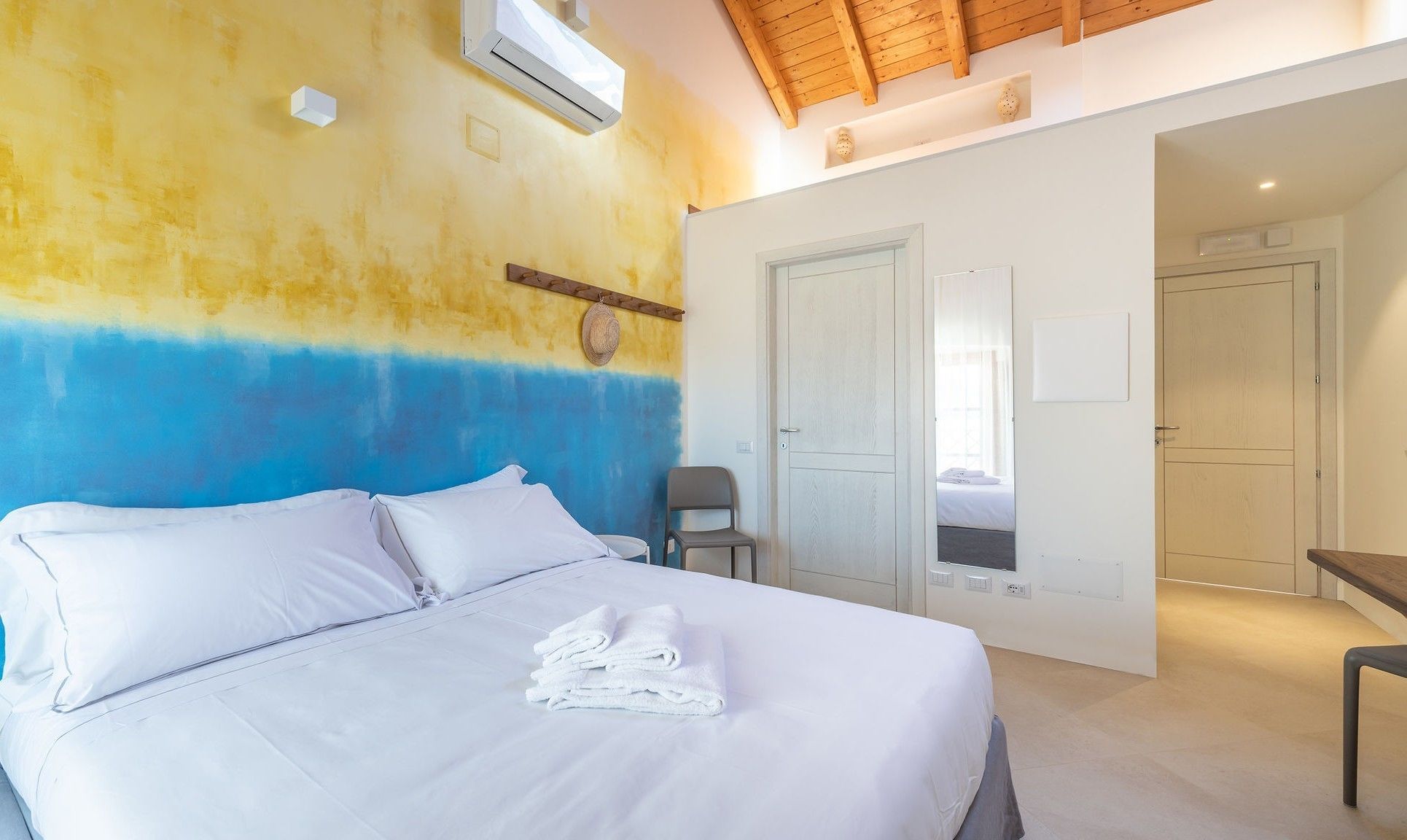 A bedroom with a bed, a chair, and a door leading to another room.