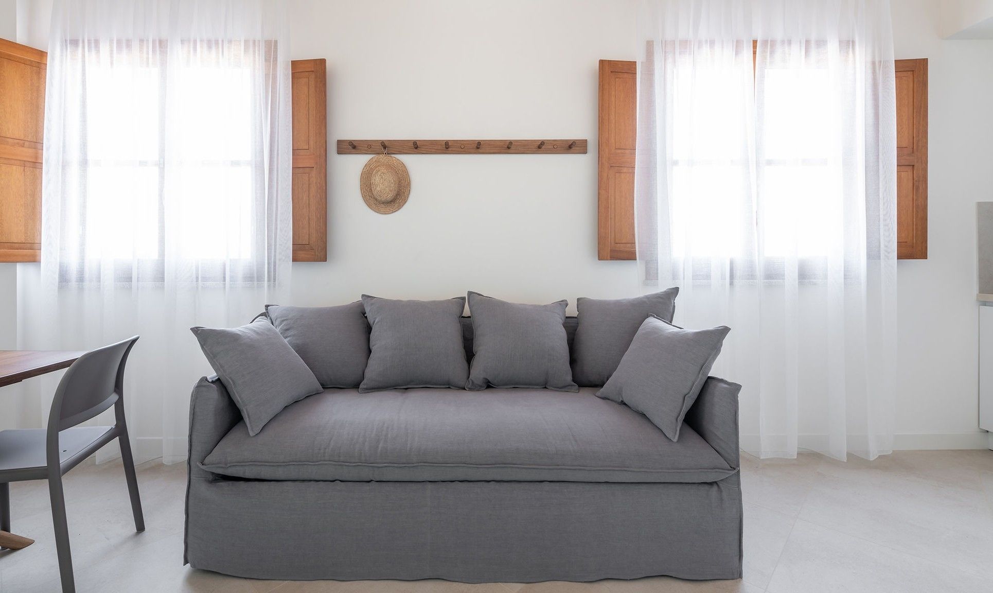 Una sala de estar moderna con un sofá gris, un perchero de madera y un tapiz tejido en la pared.