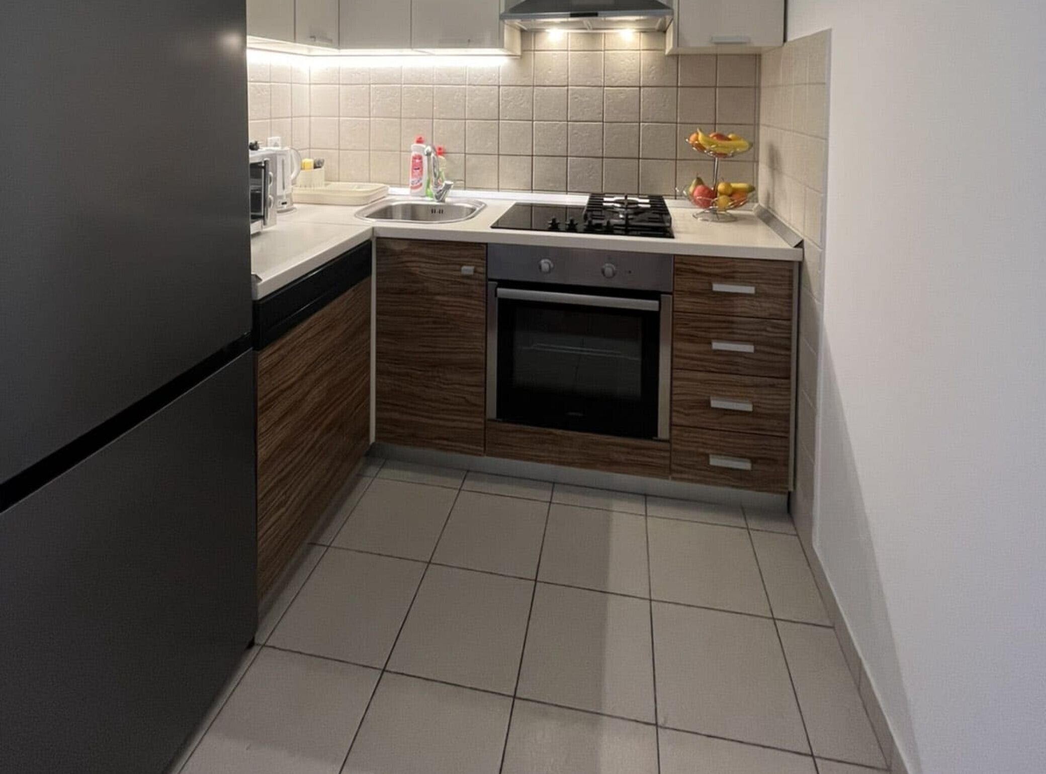 Une cuisine équipée d’une cuisinière, d’un four, d’un évier et d’un panier à fruits.