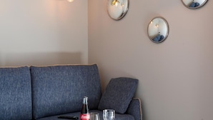 A modern living room with a blue sofa, a wooden coffee table, a bottle of Coca-Cola, and a glass of orange juice. - Le Bel Abri (Annecy)